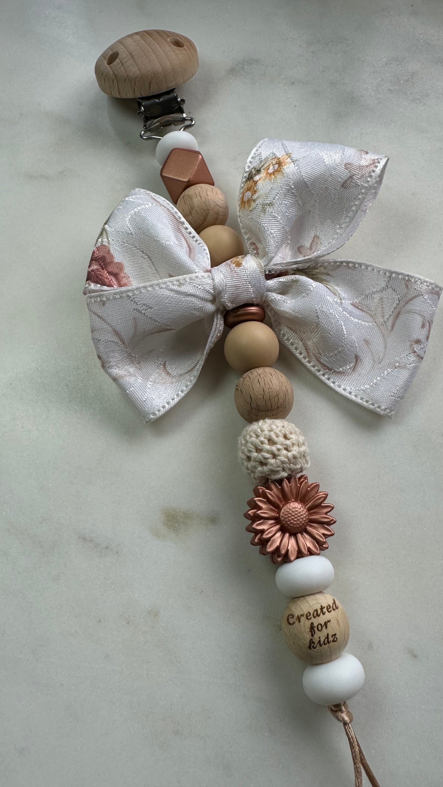 Speenkoord koperbloem met strik, koperkleurige accenten, wit en houtlook.